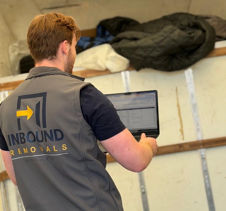 The Inbound Removals logo on the back of Harry's gilet as he works on the CRM in the van